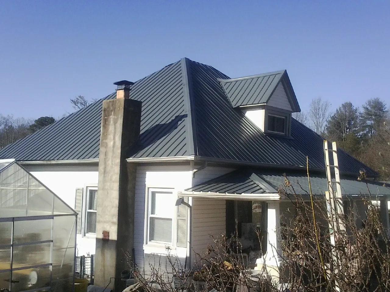 Dark blue standing seam metal roof on a white farmhouse with dormer — Slate & Tile Roof Repair by Roofing Brothers in Naches