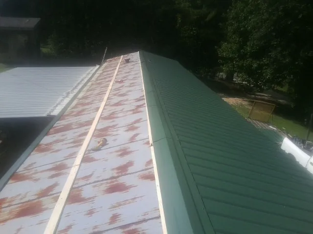 Old rusted panels beside newly installed green metal roofing — Wind Damage Roof Repair by Roofing Brothers in Naches