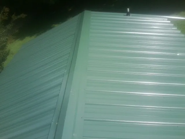 New green metal panels meeting at the ridge of a roof — Flat Roof Repair work by our crew in Naches