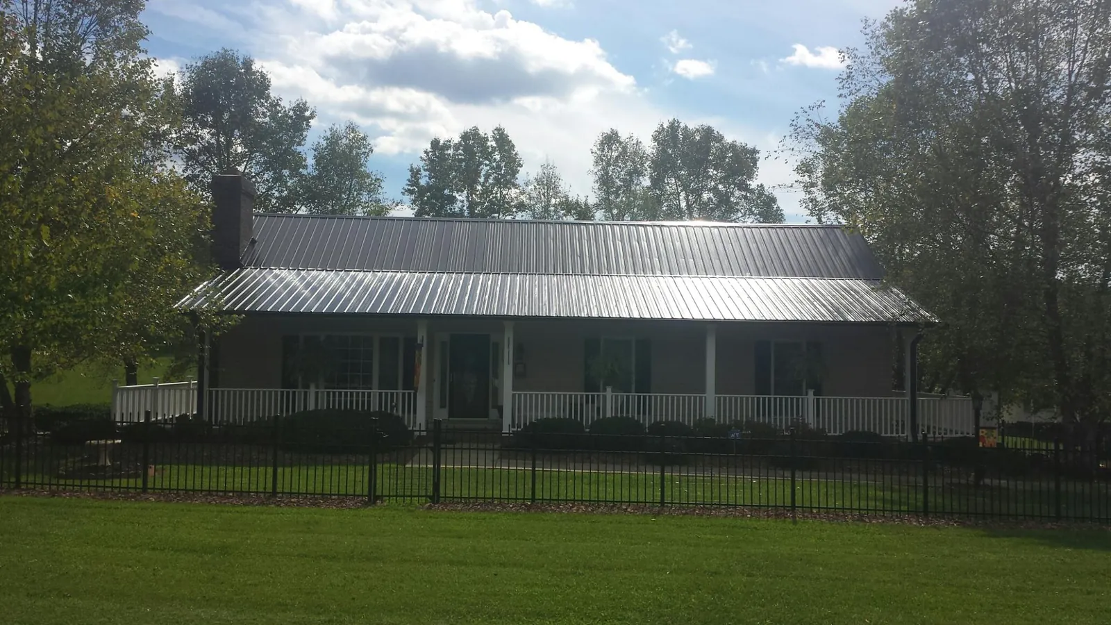 Gray metal roof on a brick ranch with a full width front porch — Gutter Guard Installation work by our crew in Naches