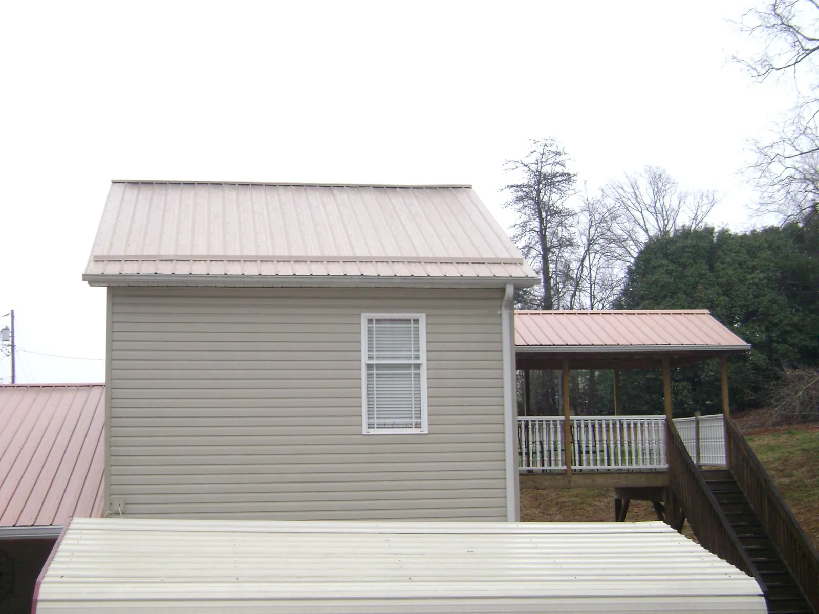 Tan metal roofs on a two story addition and attached porch, from a Roof Replacement job in Naches