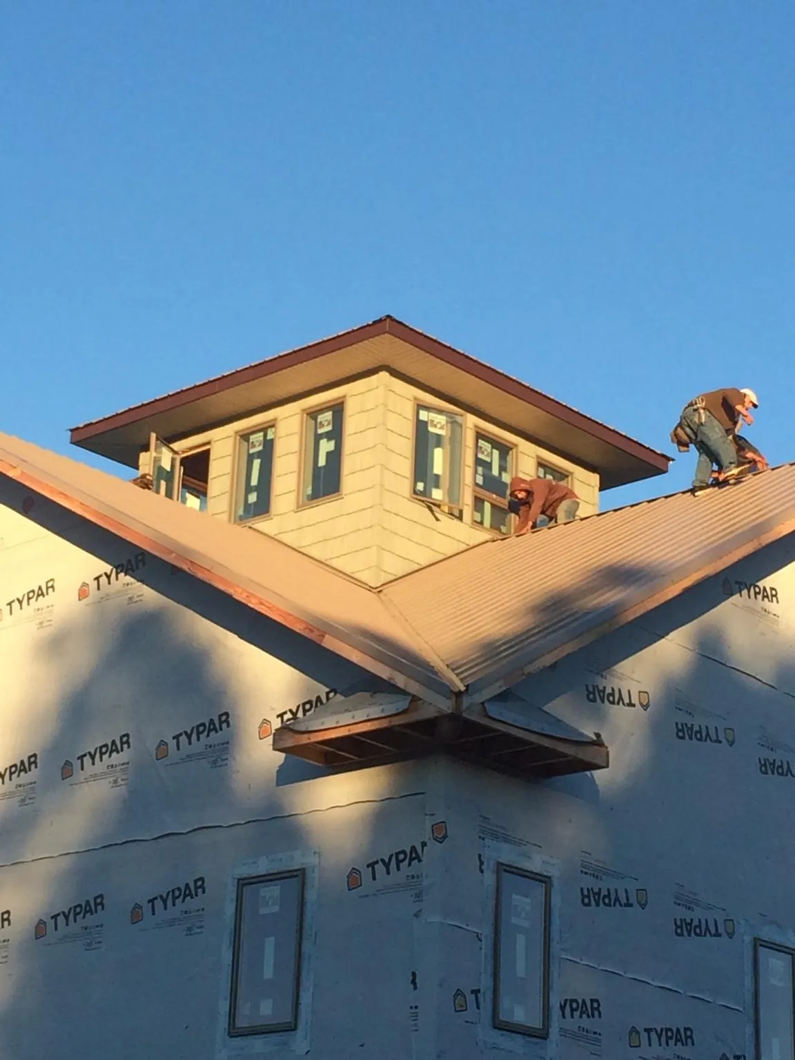 Roofers working around a rooftop cupola on a new metal roof at sunset — Roof Waterproofing in Naches by Roofing Brothers